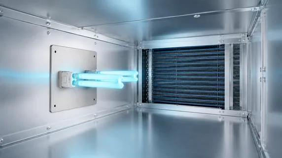 The installed Classic lamp glowing blue inside the air handler, facing the coil.