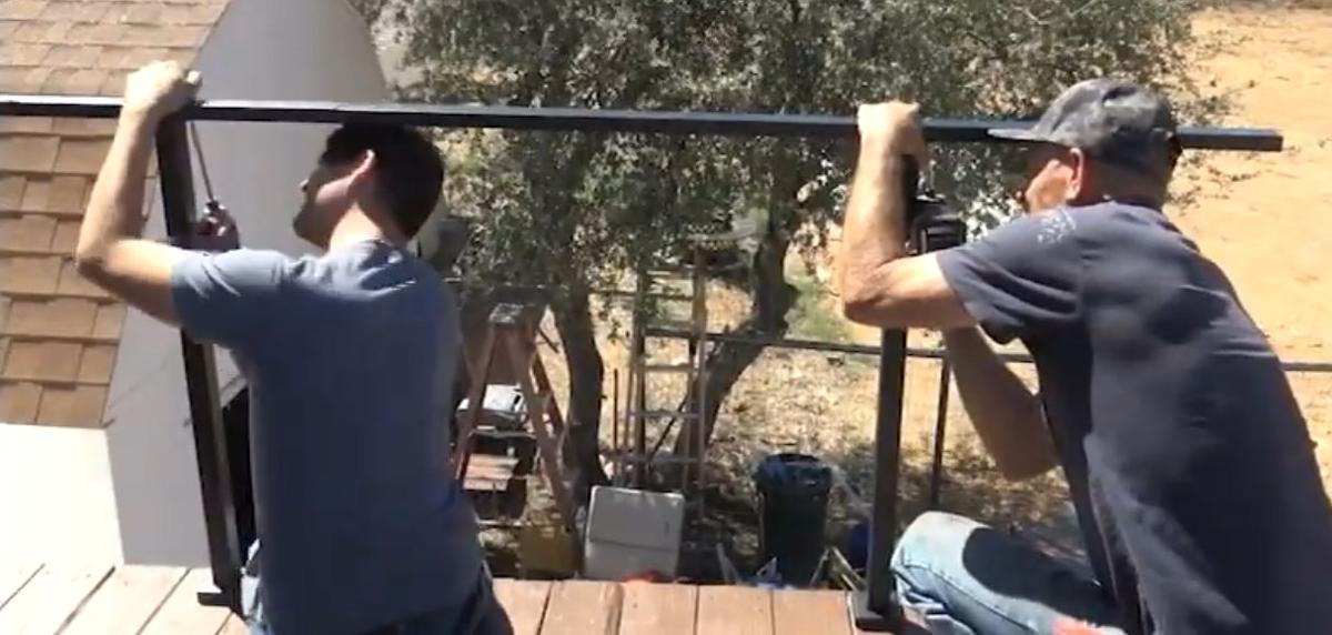 Two installers fitting a CR cable railing on a deck