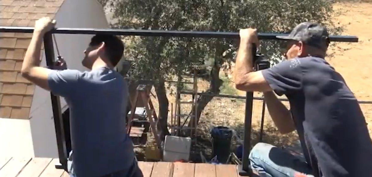 Two installers fitting a CR cable railing on a deck